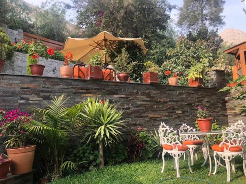 un jardín con sillas, mesas y plantas en una pared de ladrillo en Casa Campo Machu Picchu - Club Los Girasoles, Chaclacayo, en Chaclacayo