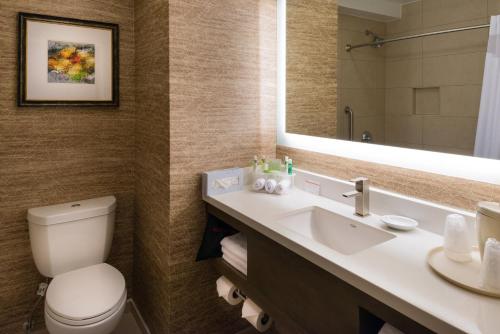 a bathroom with a toilet and a sink and a mirror at Holiday Inn Express & Suites Pasadena - Los Angeles by IHG in Pasadena