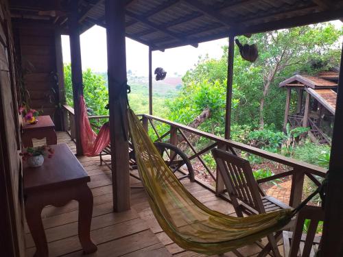 porche con hamaca, mesa y sillas en Nature House Eco-Lodge& Trekking, en Banlung