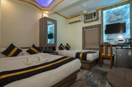 a hotel room with two beds and a table at Snehamaya Spa & Resort in Digha