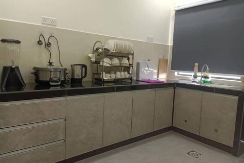 a kitchen with a black counter and a large screen at KS 80 Homestay (15pax)4R3B ~WiFi~ near Jetty in Kuala Selangor