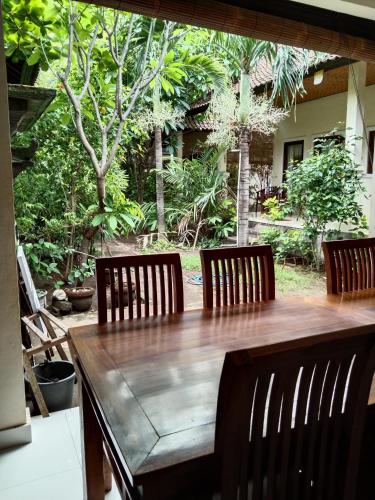 a wooden table with four chairs around it with a garden at Pondok Aldi Hostel in Amed