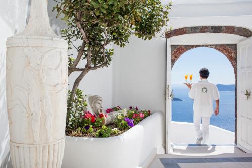a man walking through a door into a garden at The Tsitouras Collection in Firostefani