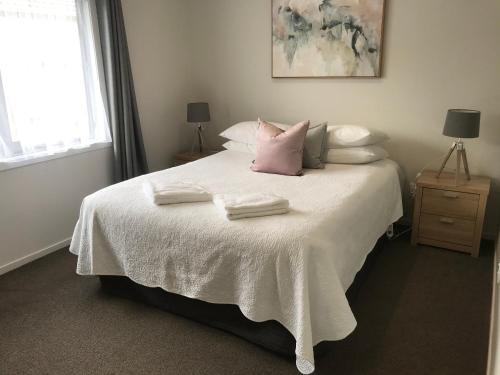 um quarto com uma cama branca com duas toalhas em Rose Apartments Central Rotorua- Accommodation & Private Spa em Rotorua