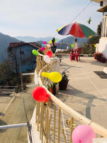 a bunch of colorful balloons on a balcony with an umbrella at Aqua De Vida in Bhowāli