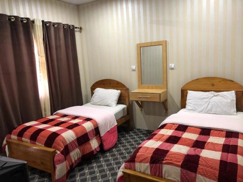 a hotel room with two beds and a mirror at Madina Hotel 2 in Gilgit