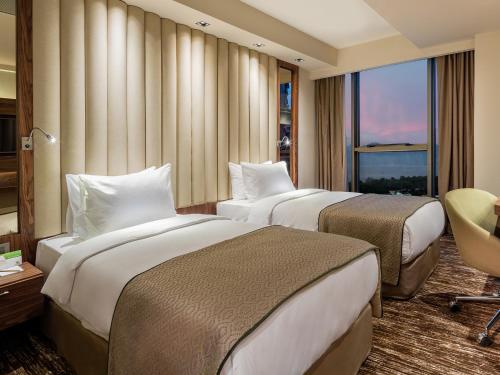 a hotel room with two beds and a window at Holiday Inn Antalya - Lara by IHG in Antalya