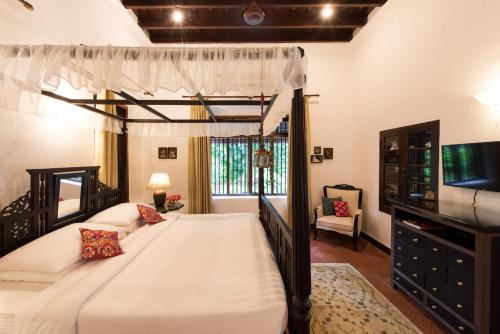 a bedroom with a canopy bed and a tv at amã Stays & Trails, Ambika Vilas in Trivandrum
