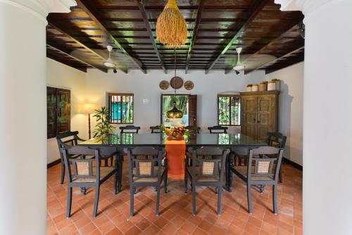 a dining room with a black table and chairs at amã Stays & Trails, Ambika Vilas in Trivandrum