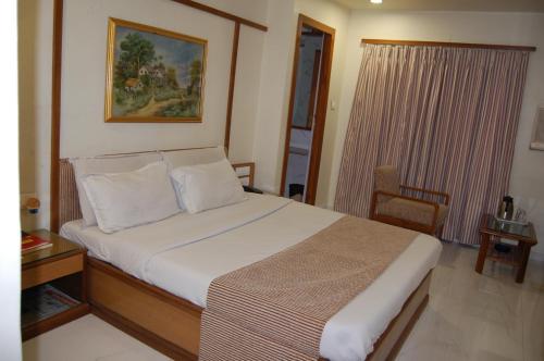 1 dormitorio con cama, mesa y ventana en Hotel Vice President en Ahmedabad