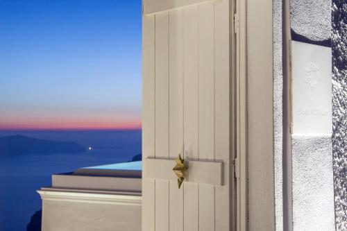 an open door with a view of the ocean at The Tsitouras Collection in Firostefani