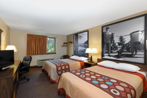 a hotel room with two beds and a flat screen tv at Super 8 by Wyndham Bemidji MN in Bemidji