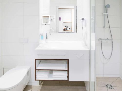 ein weißes Bad mit einem Waschbecken und einer Dusche in der Unterkunft Mercure Hotel MOA Berlin in Berlin