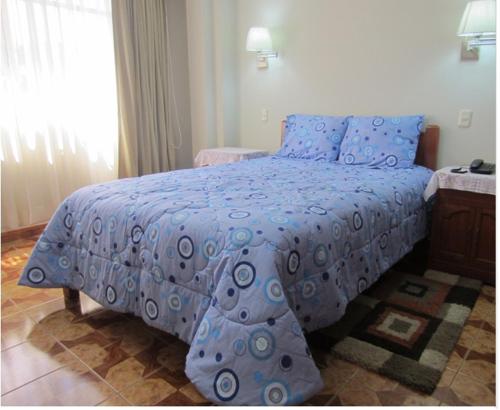 1 dormitorio con 1 cama con edredón azul en Hostal Residencial Lino, en Huaraz