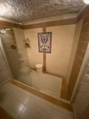 a bathroom with a shower with a toilet and a rug at Mimi Cappadocia Luxury Cave Hotel in Uchisar