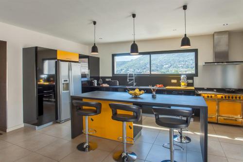 une cuisine avec un grand îlot et des tabourets de bar dans l'établissement Villa casa Luna piscine chauffée vue mer proche centre et plage de Calvi, à Calvi