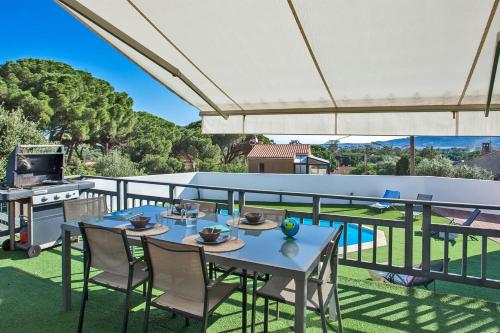 een patio met een tafel en stoelen en een grill bij Villa avec piscine chauffée et vue mer proche centre et plage de Calvi in Calvi