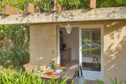 un patio con una mesa frente a una puerta en minivilla lilas indépendante à Calvi avec jardin et piscine jardin et bbq en Calvi
