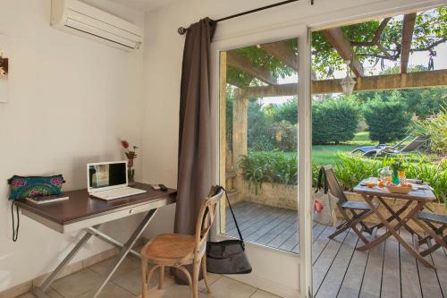 un bureau avec un bureau et une table avec un ordinateur portable dans l'établissement minivilla lilas indépendante à Calvi avec jardin et piscine jardin et bbq, à Calvi