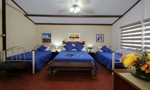 a bedroom with two beds with blue sheets and a fan at Saint Patricks Lodge in Santa Elena