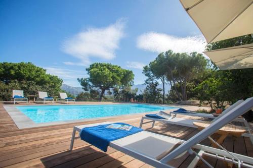 uma piscina com duas espreguiçadeiras e um guarda-sol em Villa in Calvi with warmed swimming pool garden sea view near the beach em Calvi