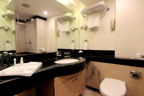 a bathroom with a sink and a toilet and a mirror at Fortel in Chennai