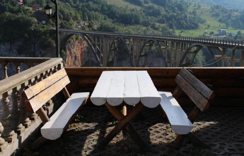 a picnic table and benches on a balcony with a bridge at Tara Bridge Castle in Žabljak