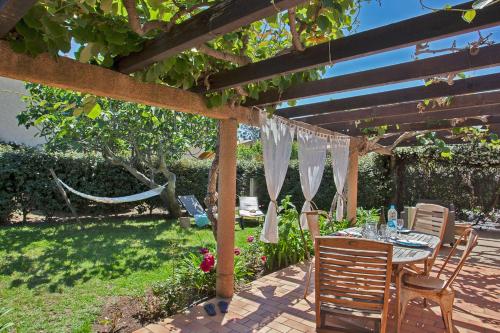 eine Terrasse mit einem Tisch und Stühlen unter einer Pergola in der Unterkunft maison kiwi avec piscine chauffée terrasse jardin et bbq à Calvi in Calvi