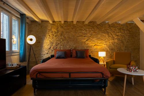 a bedroom with a bed and a stone wall at Dolce NÎMES CENTRE in Nîmes