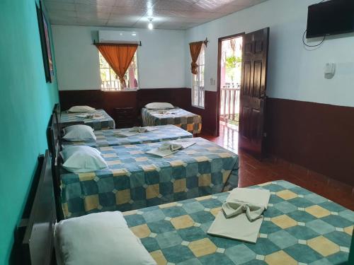 um quarto com três camas e uma tv nele em Papaya Lodge em La Libertad