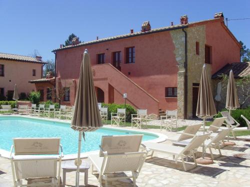 a pool with chairs and umbrellas next to a building at Toscana Relax Gambassi Terme in Gambassi Terme