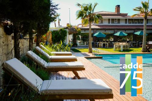 a resort with a pool with benches and tables at Cadde 75 Luxury Hotel - Alaçatı in Alaçatı