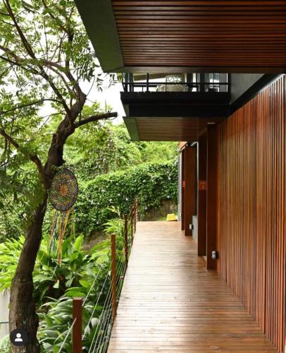 a wooden walkway leading to a building with a tree at Vila Bambu Ilhabela, Santa Tereza in Ilhabela