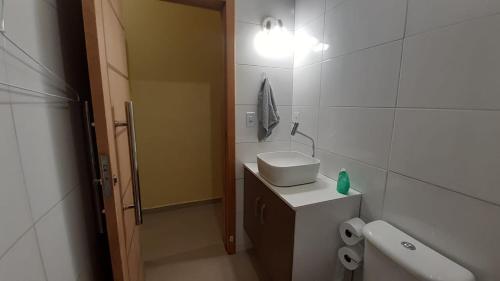 ein Bad mit einem Waschbecken, einem WC und einer Lampe in der Unterkunft Praia Grande Apartamento Aconchegante pertinho da Praia - 300m in Praia Grande