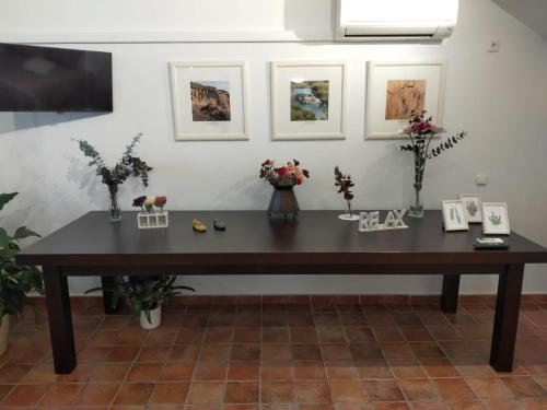 uma mesa de madeira num quarto com flores e fotografias em Casabobastro em Ardales