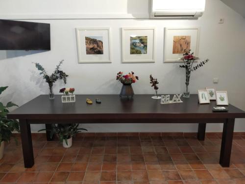 a wooden table in a room with flowers and pictures at Casabobastro in Ardales