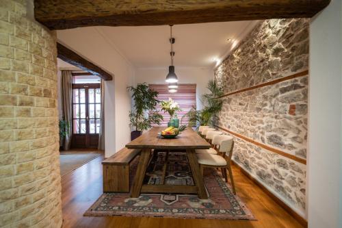 a dining room with a table and a stone wall at Four Season Maison in Kavala