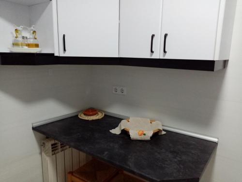 a kitchen with white cabinets and a black counter top at Holiday Home La Asomailla in Hoyos del Espino
