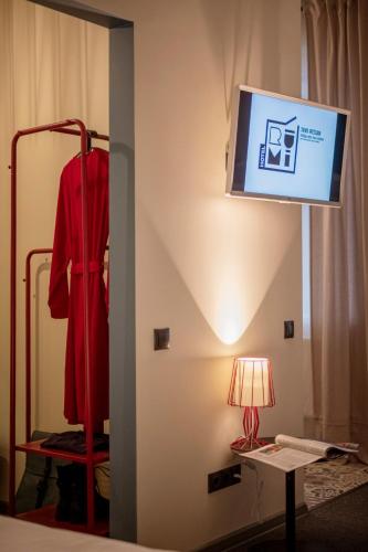 a room with a tv and a red robe and a lamp at RUMI Hotel with Self Check-In in Jēkabpils