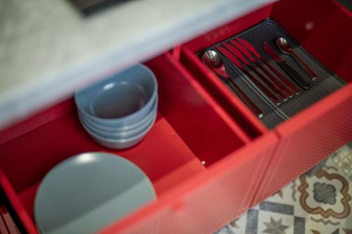 a red lunch box with a utensil and a bowl at RUMI Hotel with Self Check-In in Jēkabpils