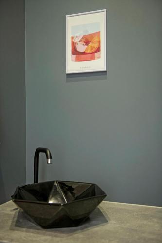 a black sink on a counter with a picture on the wall at RUMI Hotel with Self Check-In in Jēkabpils