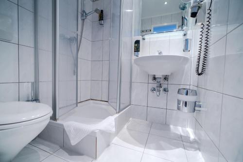 een witte badkamer met een toilet en een wastafel bij Hotel Tiergarten Berlin in Berlijn