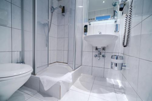 a white bathroom with a toilet and a sink at Hotel Tiergarten Berlin in Berlin