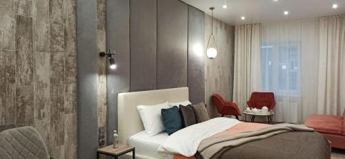 a bedroom with a bed and two red chairs at Citylife Boutique Hotel in Kharkiv