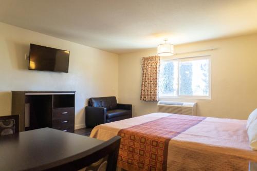 a hotel room with a bed and a chair and a window at Maywood Inn in Maywood