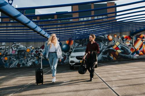 a man and woman walking down a bridge with their luggage at The Hague Teleport Hotel in The Hague