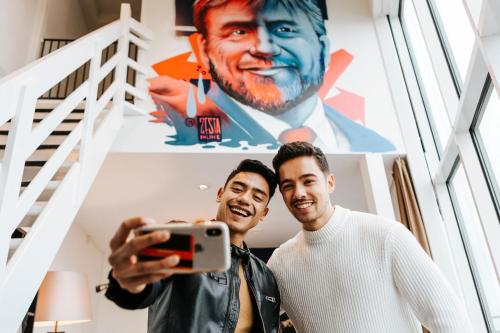 two men taking a picture in front of a poster at The Hague Teleport Hotel in The Hague