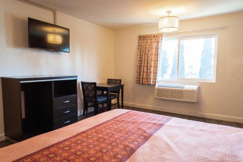 a bedroom with a bed and a television and a window at Maywood Inn in Maywood