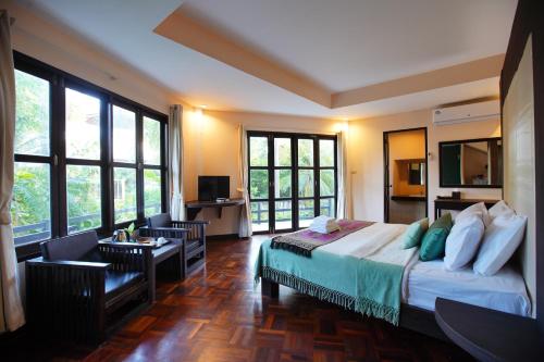 a bedroom with a bed and a room with windows at Tanaosri Resort Pranburi in Pran Buri
