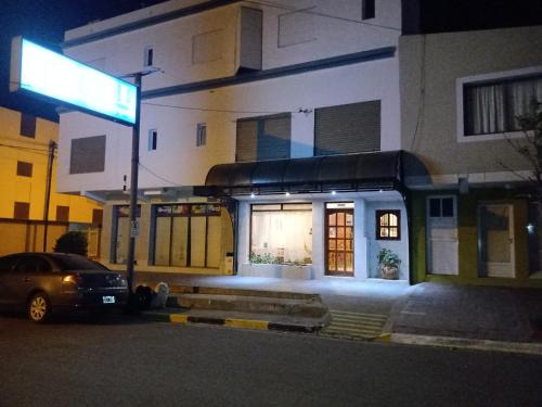une voiture garée devant un bâtiment la nuit dans l'établissement Hotel Pilmayquen, à Las Grutas
